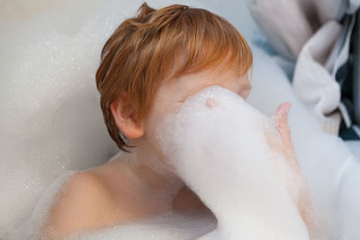 Boy taking bubble bath in bathroom