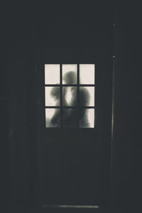 Newlywed couple kissing seen through cottage window