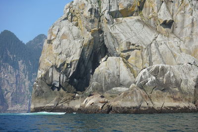 Rock formation by sea against sky