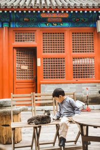 Full length of man sitting on table against building