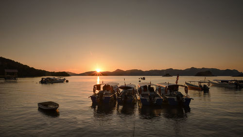 Boats moored on sea against sky during sunset