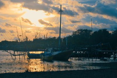 Sailboats moored in marina at sunset