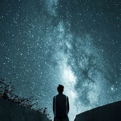 Rear view of man looking at star field in sky at night