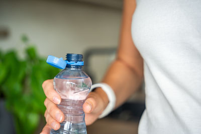 Midsection of woman holding bottle