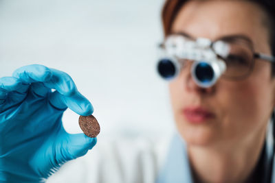 Numismatics expert examines a collection of coins, using magnifying goggles