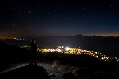 Silhouette man standing on mountain against sky at night