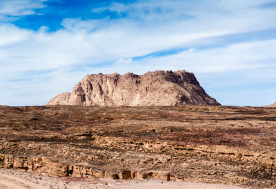 Rock formations on landscape against cloudy sky