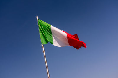 Low angle view of flag against clear blue sky