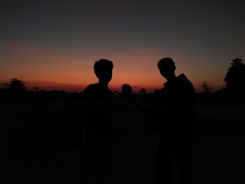 Silhouette man standing against orange sky during sunset