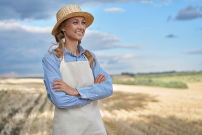 Full length of a smiling young woman standing on field