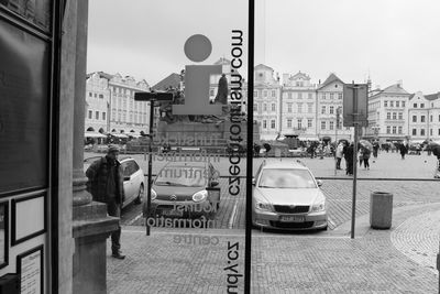 Reflection of woman on road in city against sky