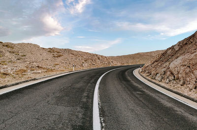 Empty road with with dividing line. rocky terrain, beautiful sky.