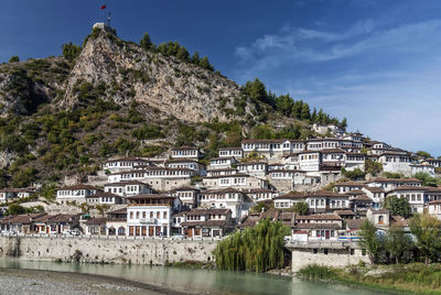 Low angle view of houses and mountains against blue sky