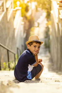Portrait of cute boy wearing hat sitting on steps