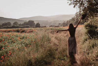 Rear view of woman standing on field against sky