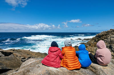 Rear view of rocks on beach against sky