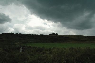 Scenic view of grassy field against cloudy sky