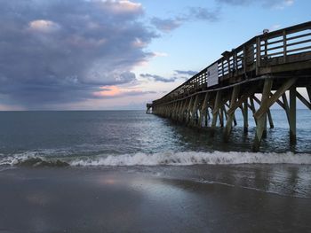 Pier on sea against cloudy sky