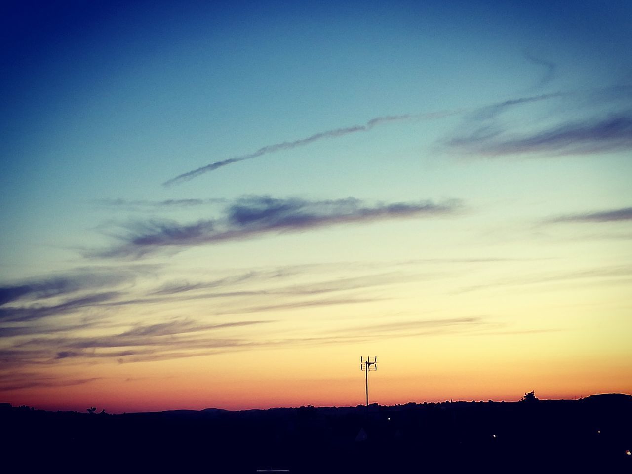 SILHOUETTE OF ELECTRICITY PYLON AGAINST SUNSET SKY