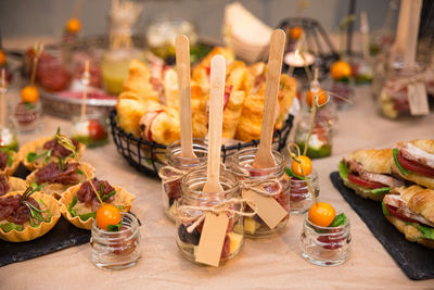 Catering in jars with wooden forks. lots of cold snacks, croissant sandwiches, tartlets, canapés