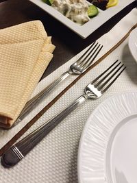 High angle view of forks with napkins and plate on table