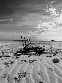 Deck chairs on beach against sky