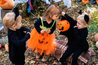 Happy kids in halloween costumes having fun in halloween decorations outdoor