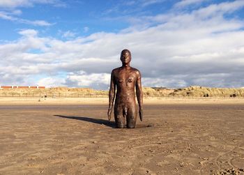 Man statue in desert against sky