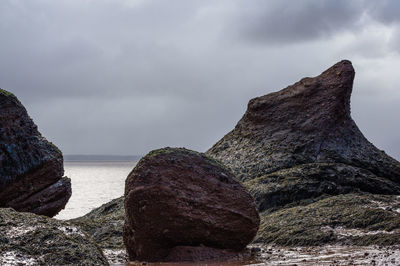 Rocks at beach against sky