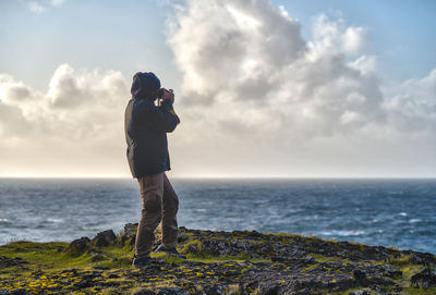 Rear view of woman standing on beach against sky