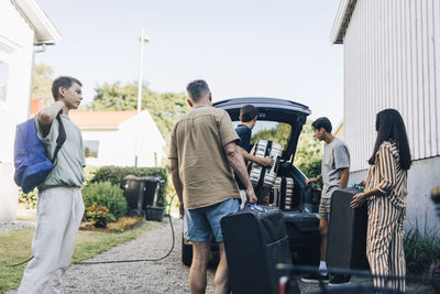 Family loading luggage in car trunk for vacations while standing in back yard