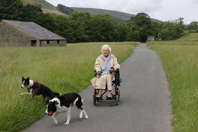 Mature woman in wheelchair playing with two dogs