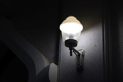 Low angle view of illuminated light bulb on wall