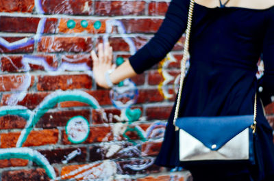 Midsection of woman touching graffiti wall