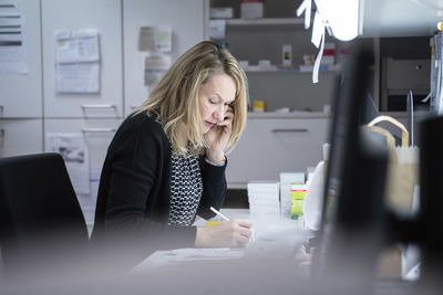 Woman talking on smart phone sitting at desk