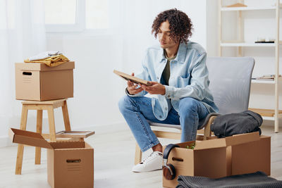 Young woman using digital tablet while sitting on sofa at home