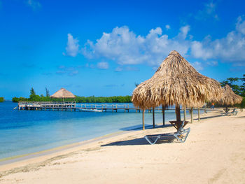 Palapa on beach against blue sky