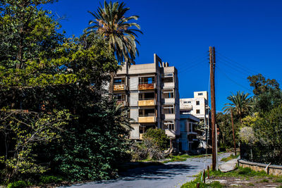 Trees and buildings against clear blue sky