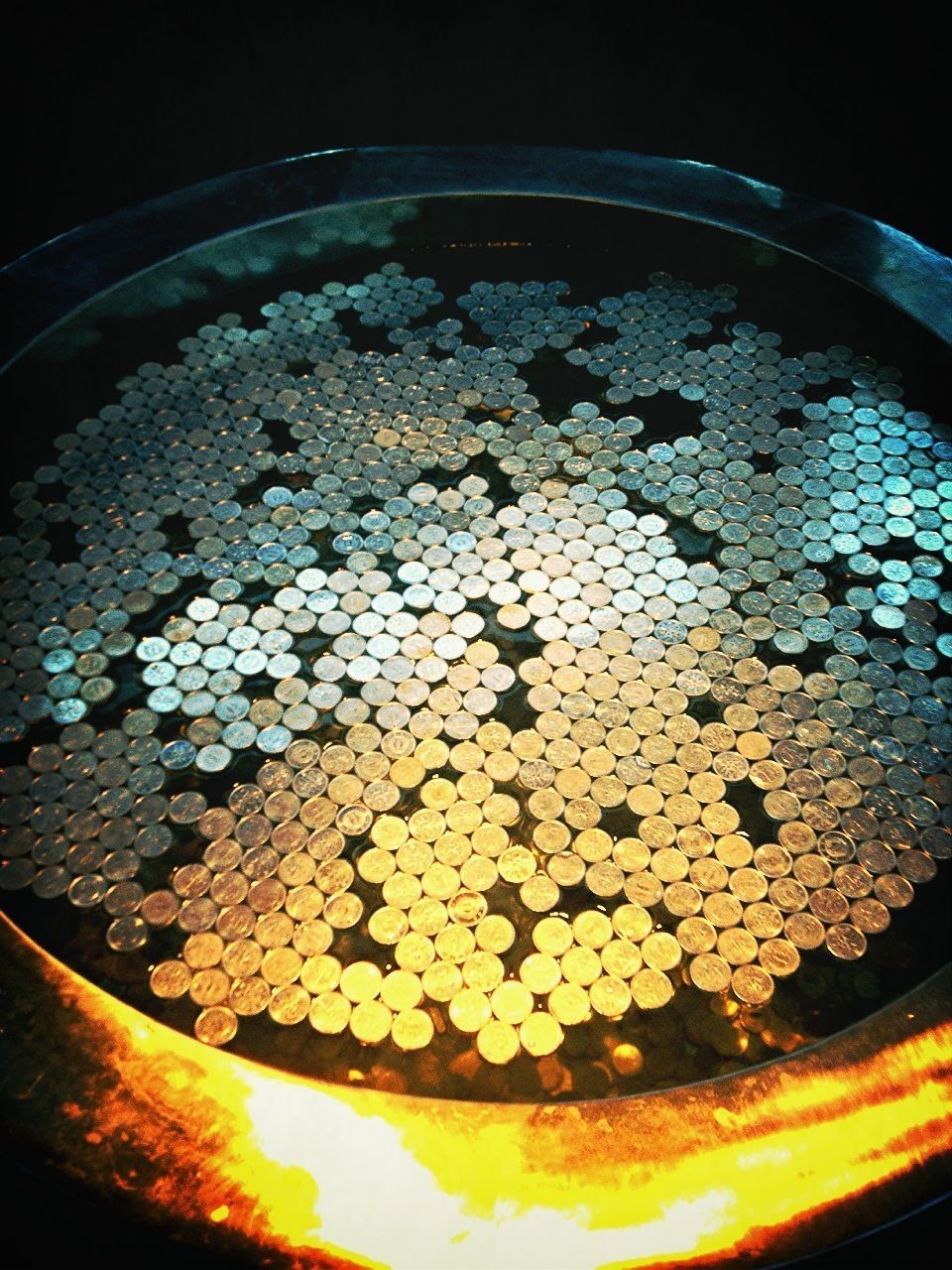 indoors, high angle view, circle, night, no people, close-up, abundance, stone - object, heat - temperature, directly above, large group of objects, metal, container, preparation, built structure, old, still life, reflection