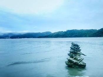 Stack of rocks in lake against sky