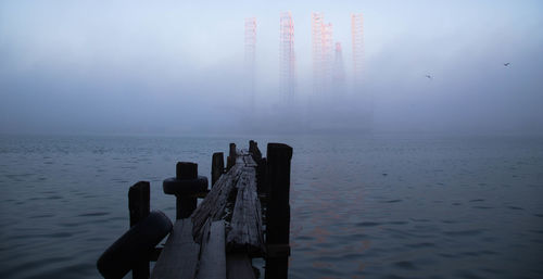 Wooden posts in sea against sky