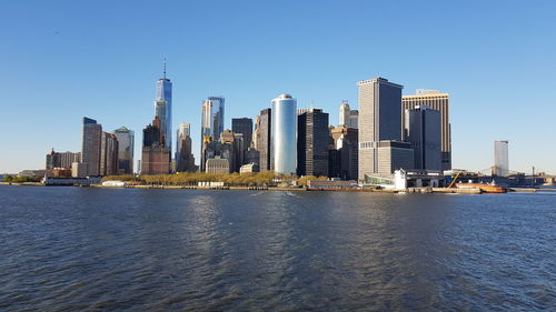 Sea by modern buildings against clear sky