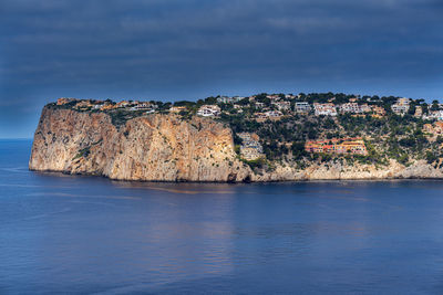 Rock formations by sea against blue sky