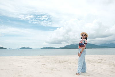 Woman standing at beach against sky