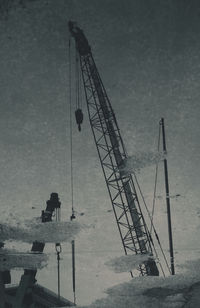 Silhouette cranes at construction site against sky