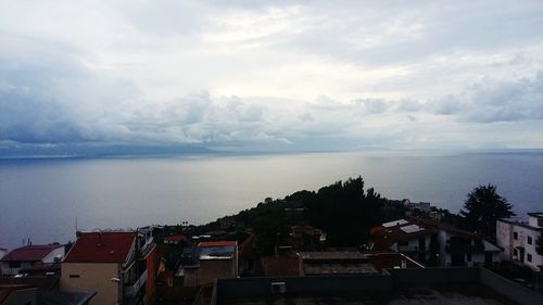 Houses in town by sea against sky