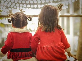 Rear view of girl standing against wall