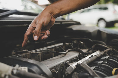 Cropped hand of man repairing engine of car