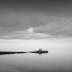 Pier amidst sea against cloudy sky