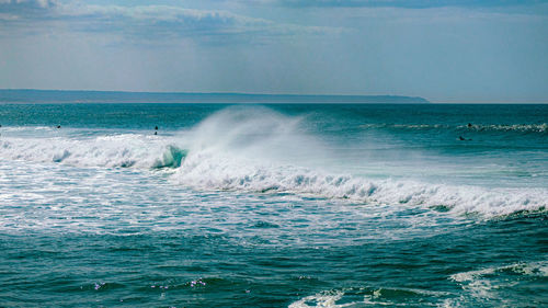 Waves splashing on sea against sky